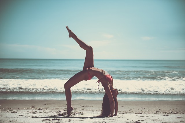 cvičící žena v plavkách na pláži – plážová jóga
